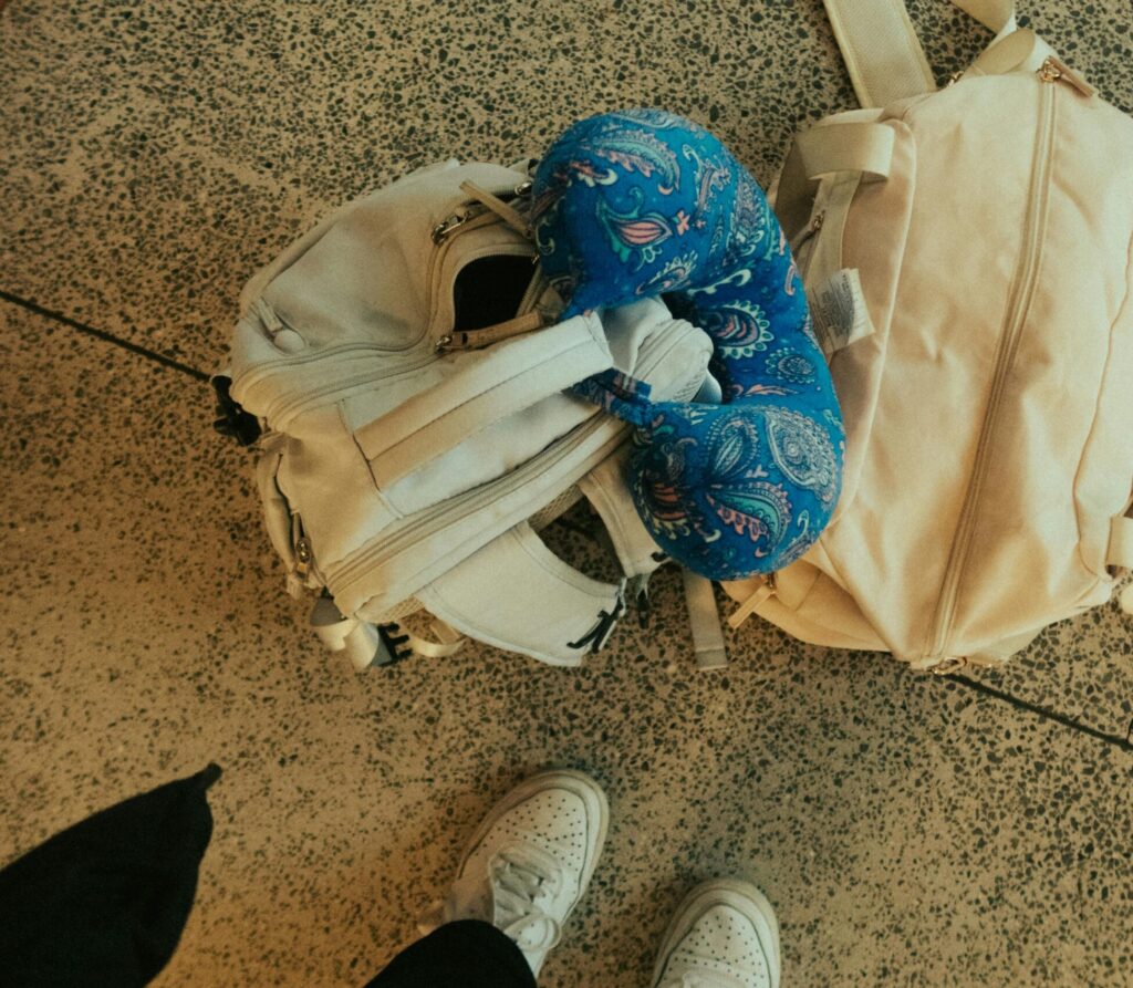 Our Amazon Travel Essentials Top view of luggage, backpack, and neck pillow at airport, ready for travel.