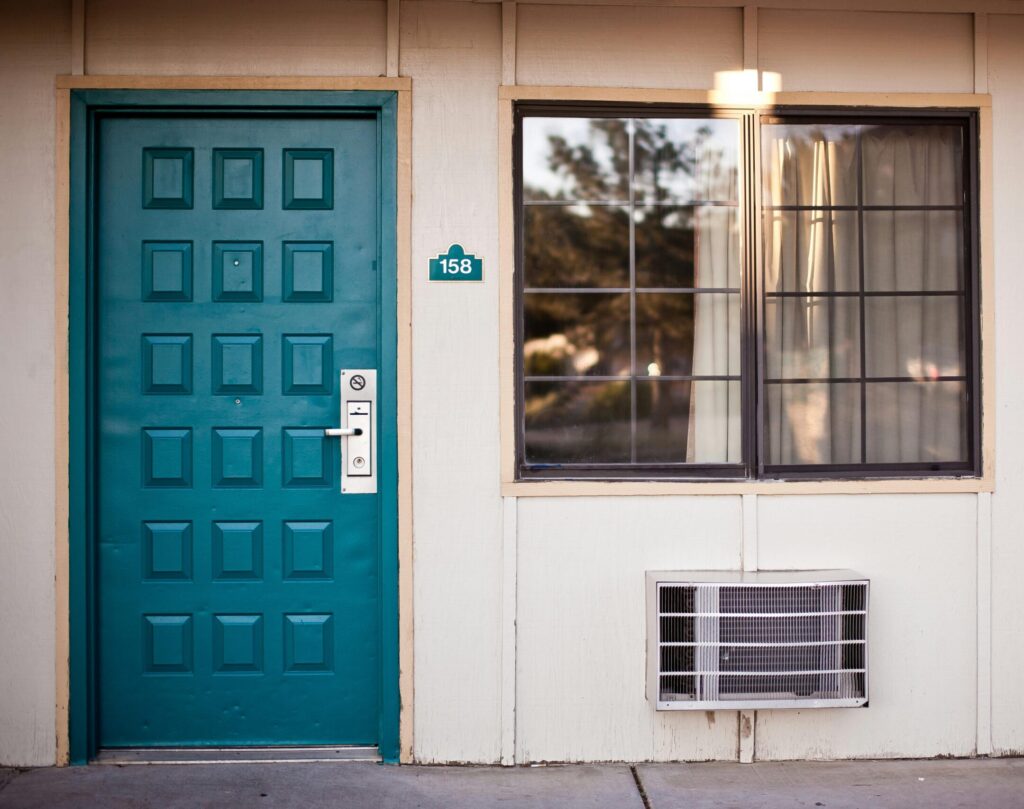 Our Amazon Travel Essentials Front view of a teal door and window, typical motel exterior entrance facade.